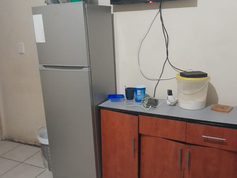 A small kitchen area featuring tiled flooring and basic base cabinetry with a laminate countertop, currently showing signs of wear and dated finishes.
