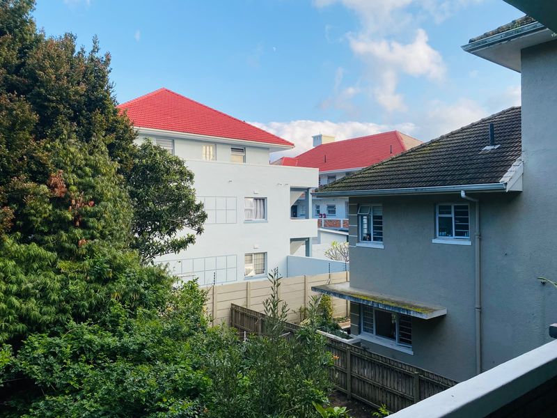 An elevated view overlooking neighboring residential properties, featuring tiled roofs, boundary fencing, and established garden greenery.