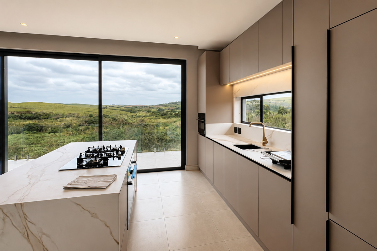 Modern kitchen featuring a stone-topped island with gas cooktop, integrated cabinetry, and expansive sliding glass doors offering scenic landscape views.