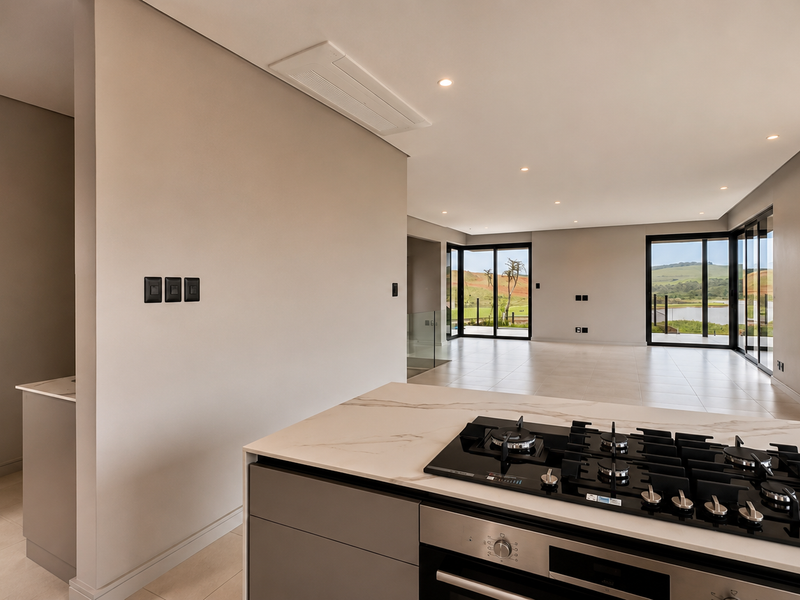 Modern open-plan kitchen and living area featuring a gas hob, stone countertops, and large sliding doors with scenic views.