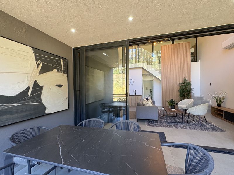 Modern open-plan living area featuring large sliding glass doors, timber slat wall detailing, and a seamless transition to the outdoor dining space.