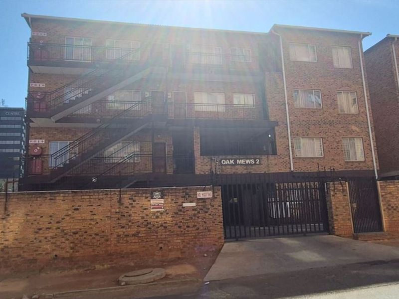 Front exterior view of Oak Mews 2 apartment complex, featuring face brick construction, external metal staircases, and secure gated access.