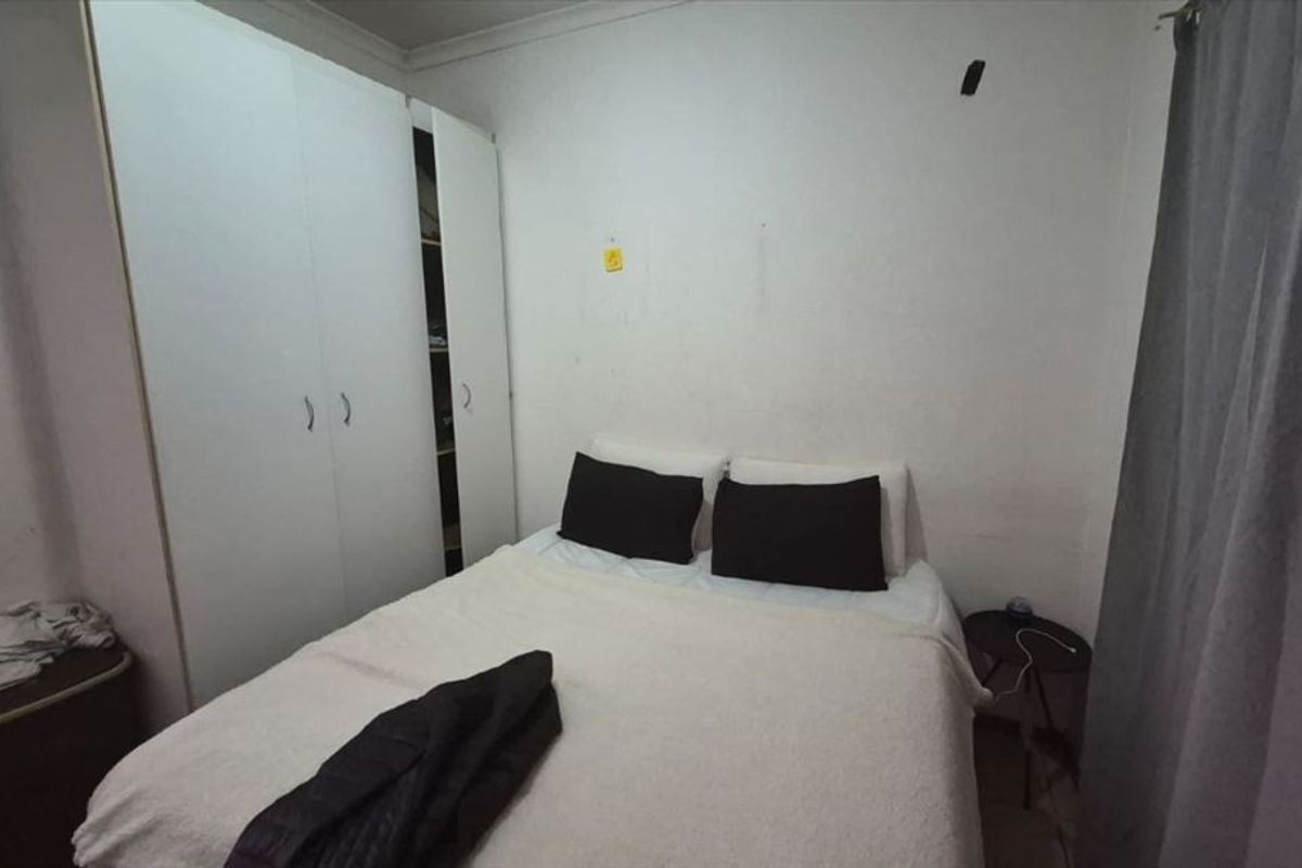 A compact bedroom featuring a built-in wardrobe and neutral finishes, requiring minor cosmetic updates to the wall surfaces.