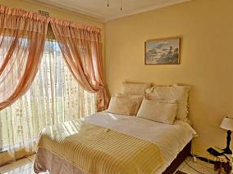 A bedroom featuring tiled flooring, a ceiling fan, and a large sliding glass door providing natural light and garden access.