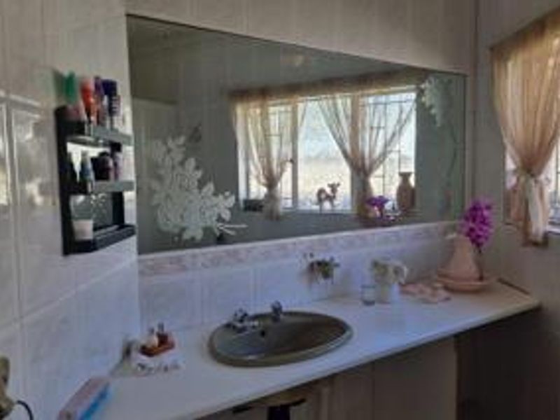 Bathroom featuring a vanity basin, large wall mirror, and tiled wall finishes with security bars on the window.