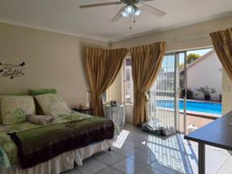 Bedroom featuring tiled flooring, a ceiling fan, and sliding glass doors providing direct access to the outdoor pool area.