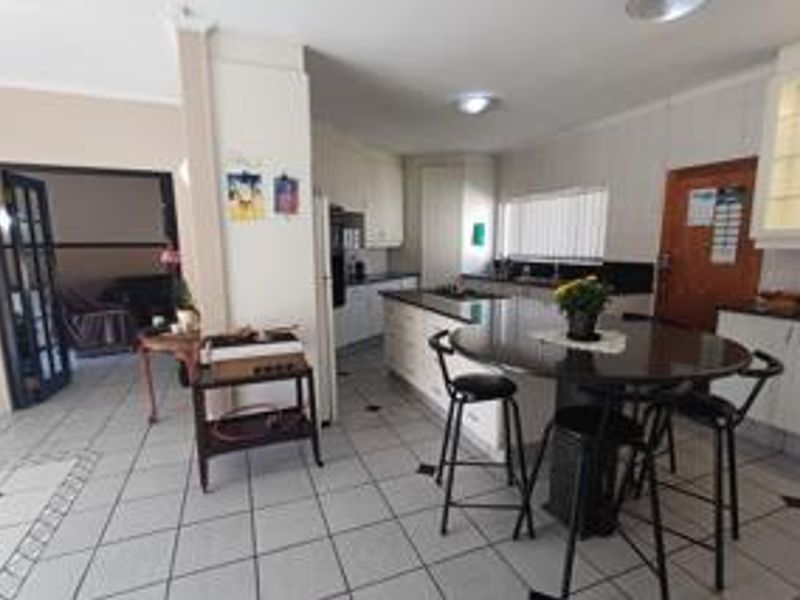 A functional kitchen featuring a central island with a granite countertop, ample built-in cabinetry, and tiled flooring, providing a practical workspace.