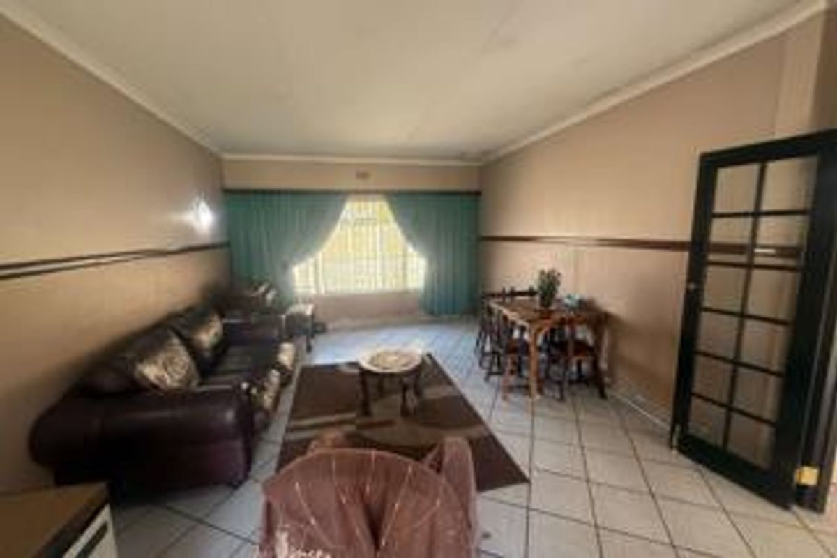 A living room featuring tiled flooring, a coved ceiling, and a classic french door, offering a functional space with potential for modern updates.