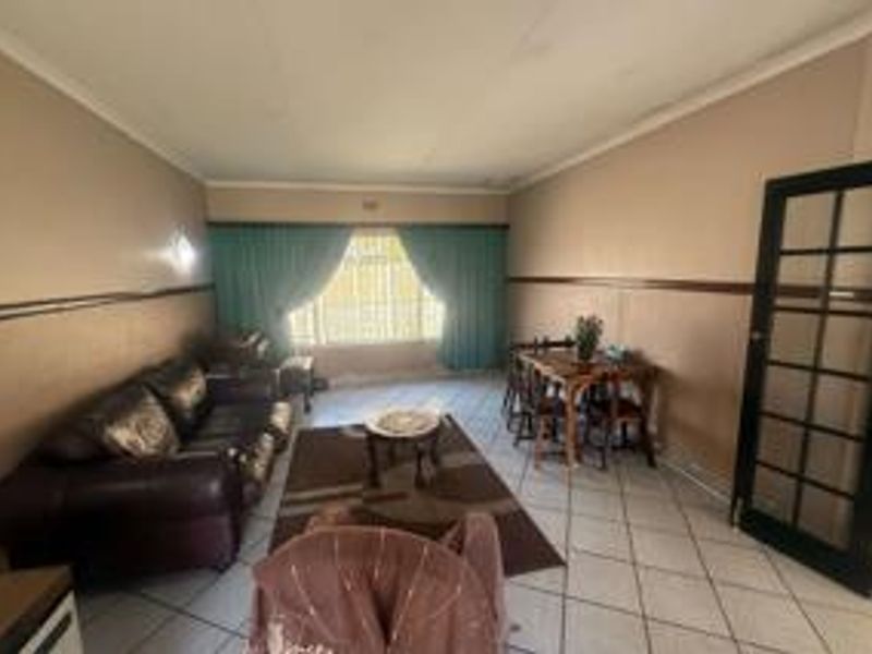 A living room featuring tiled flooring, a coved ceiling, and a classic french door, offering a functional space with potential for modern updates.