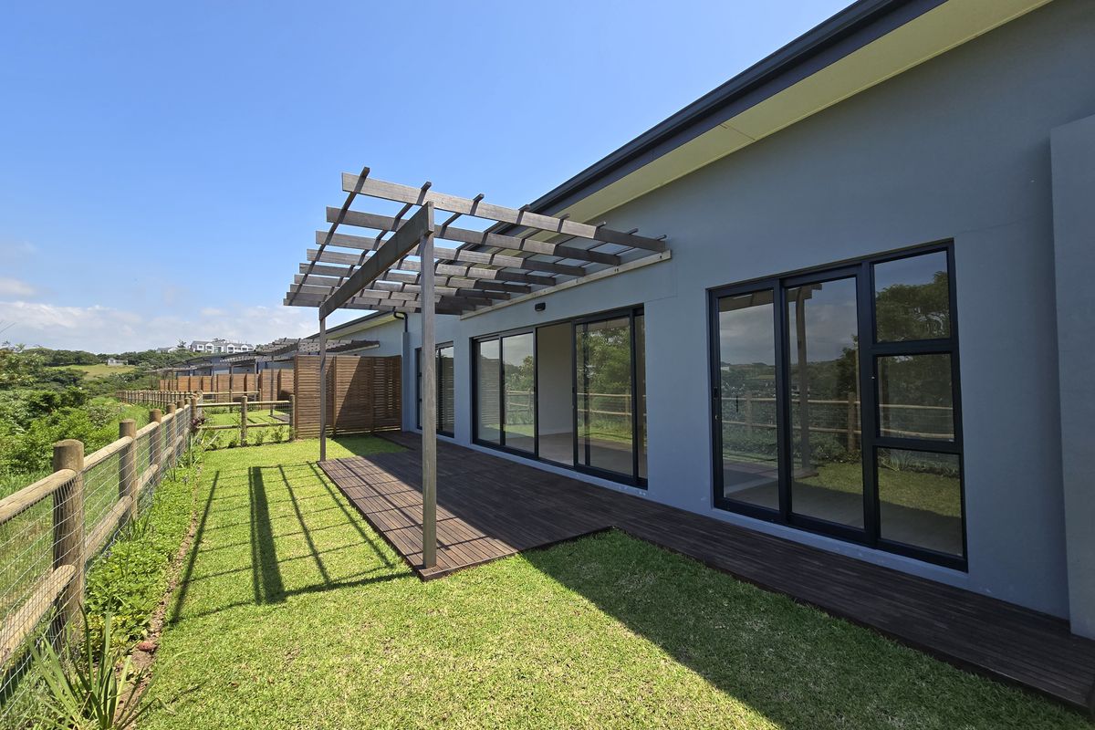 Rear exterior view of the townhouse featuring a timber deck, pergola, and large sliding glass doors opening onto a private garden area.