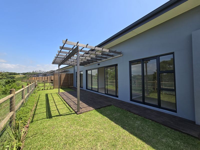 Rear exterior view of the townhouse featuring a timber deck, pergola, and large sliding glass doors opening onto a private garden area.