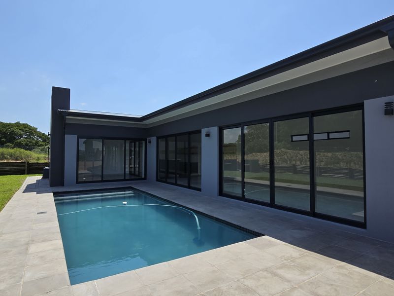 Modern townhouse exterior featuring a private swimming pool, paved patio area, and large sliding glass doors providing seamless indoor-outdoor flow.