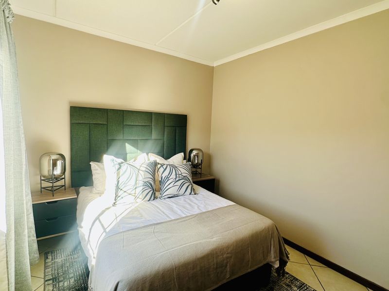 A well-lit bedroom featuring tiled flooring and a modern upholstered headboard, creating a comfortable and neutral sleeping space.