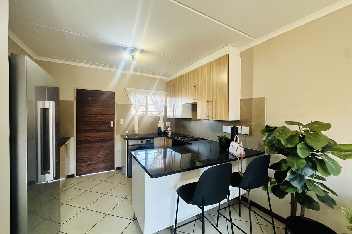 A functional kitchen featuring granite countertops, built-in cabinetry, a hob, and tiled flooring, providing a practical and well-maintained cooking space.