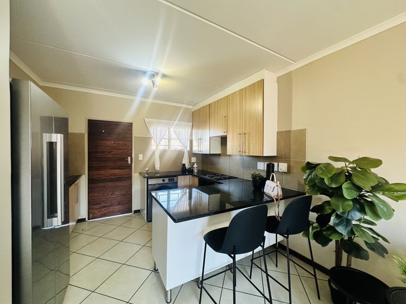 A functional kitchen featuring granite countertops, built-in cabinetry, a hob, and tiled flooring, providing a practical and well-maintained cooking space.