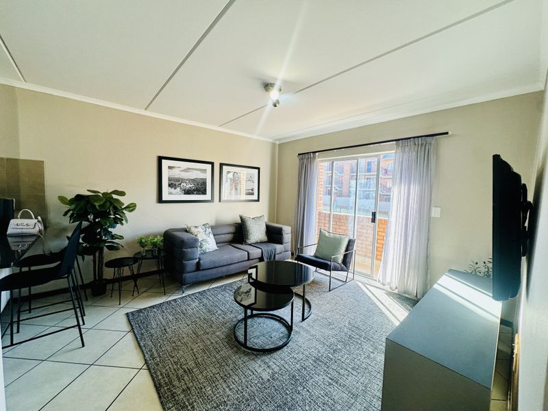 A well-lit living room featuring tiled flooring and a sliding glass door that provides access to an outdoor area.