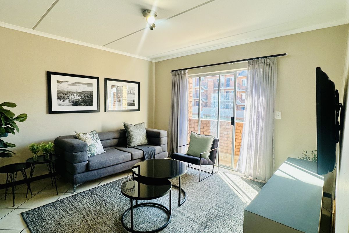 A well-lit living room featuring tiled flooring and a sliding glass door that provides access to an outdoor area.