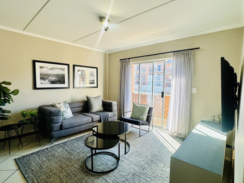A well-lit living room featuring tiled flooring and a sliding glass door that provides access to an outdoor area.