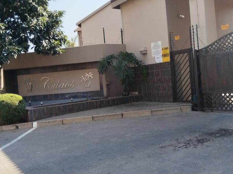 Front entrance view of the Culaos apartment complex featuring secure gated access, paved driveway, and perimeter electric fencing.