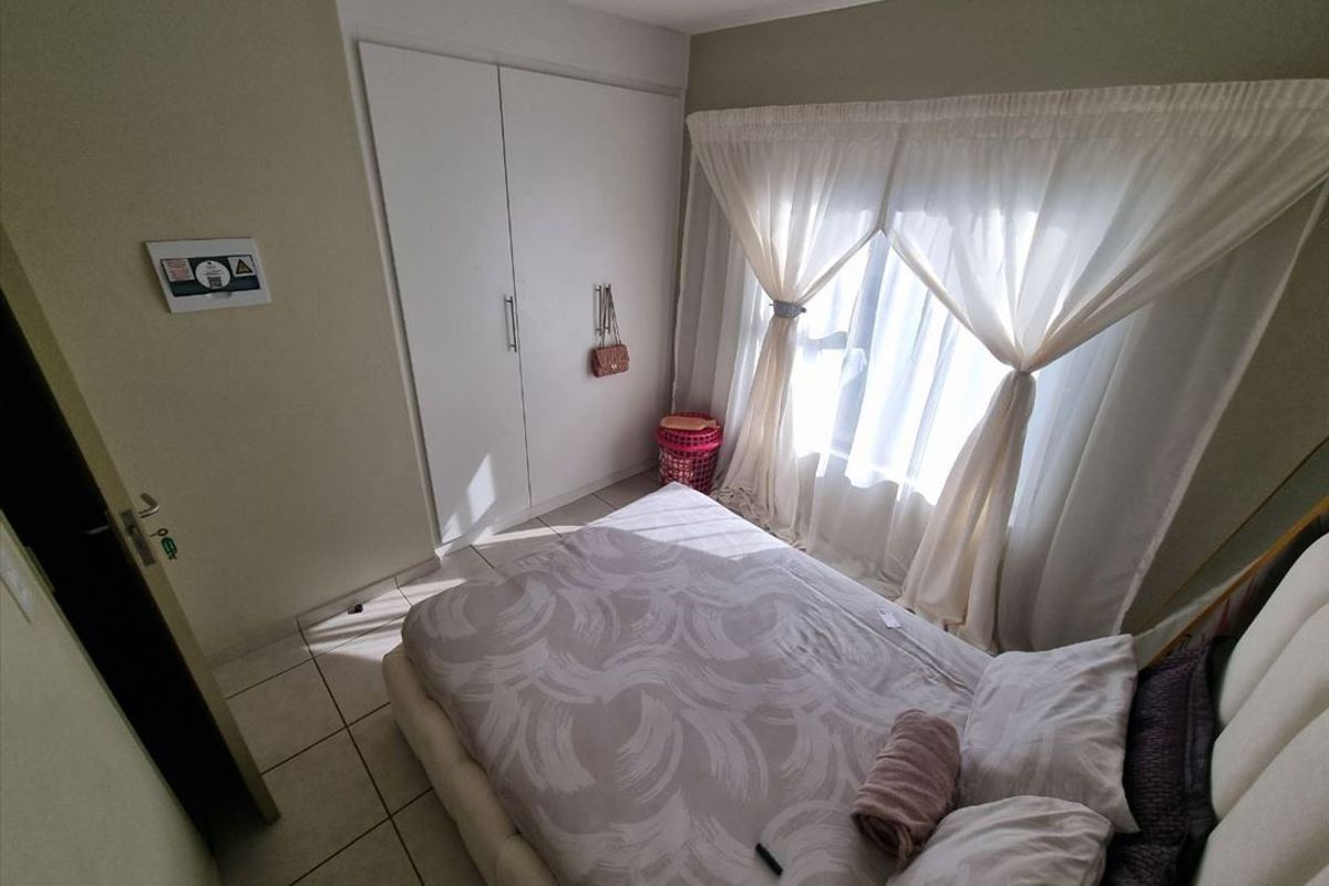 A bedroom featuring tiled flooring and a built-in wardrobe with white doors.