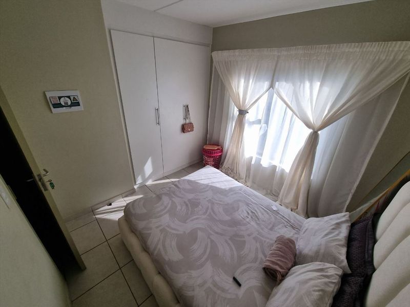 A bedroom featuring tiled flooring and a built-in wardrobe with white doors.