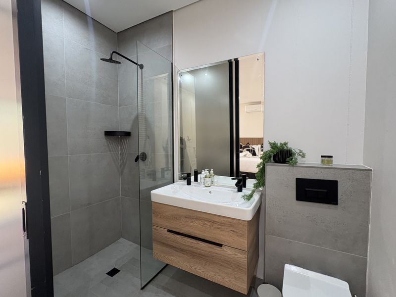 Modern bathroom featuring a walk-in shower with glass screen, wall-mounted vanity with integrated basin, and a wall-mounted toilet with concealed cistern.