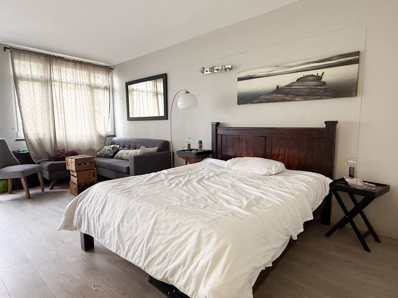 Spacious bedroom featuring light-toned laminate flooring and a large window allowing for ample natural light.