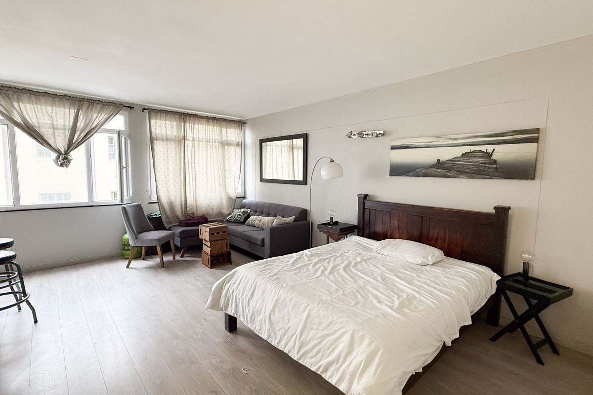 A spacious bedroom featuring light-toned laminate flooring and large windows that provide ample natural light, creating a bright and airy living environment.