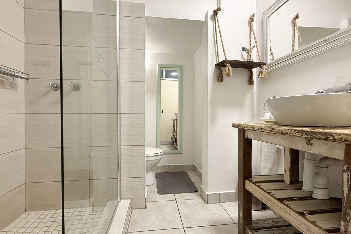 A bathroom featuring a glass-enclosed shower, tiled flooring, and a vessel sink vanity with a rustic finish.