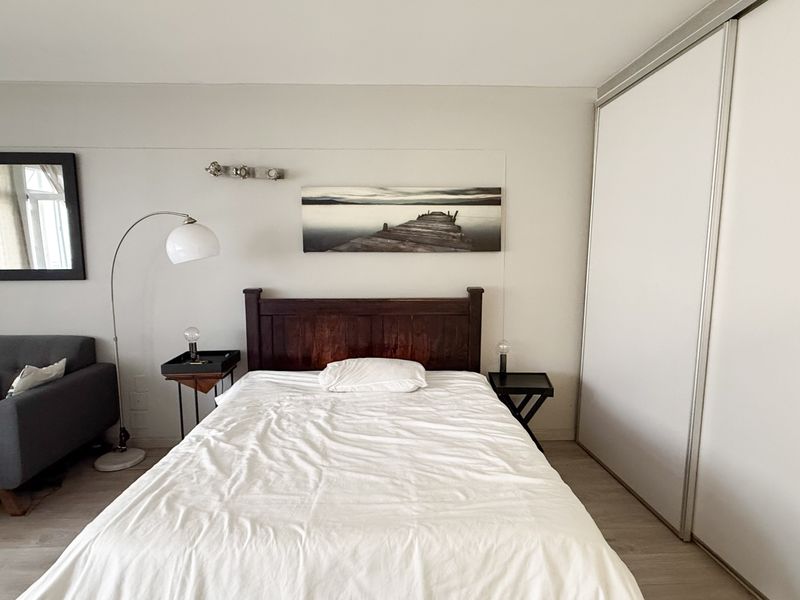 A well-maintained bedroom featuring light laminate flooring and a large built-in wardrobe with sliding doors.