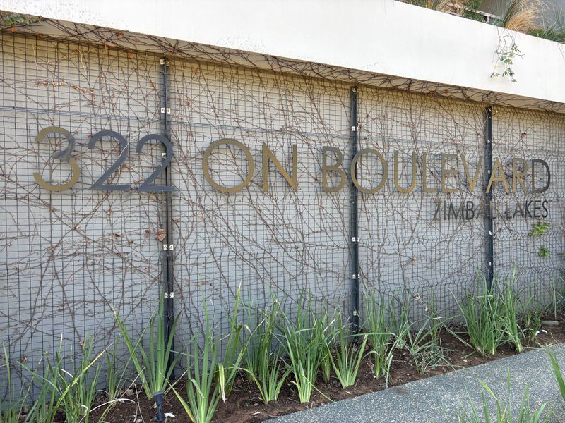 Exterior view of the building signage for 322 On Boulevard at Zimbali Lakes, featuring a metal trellis with climbing vines and a landscaped garden bed.