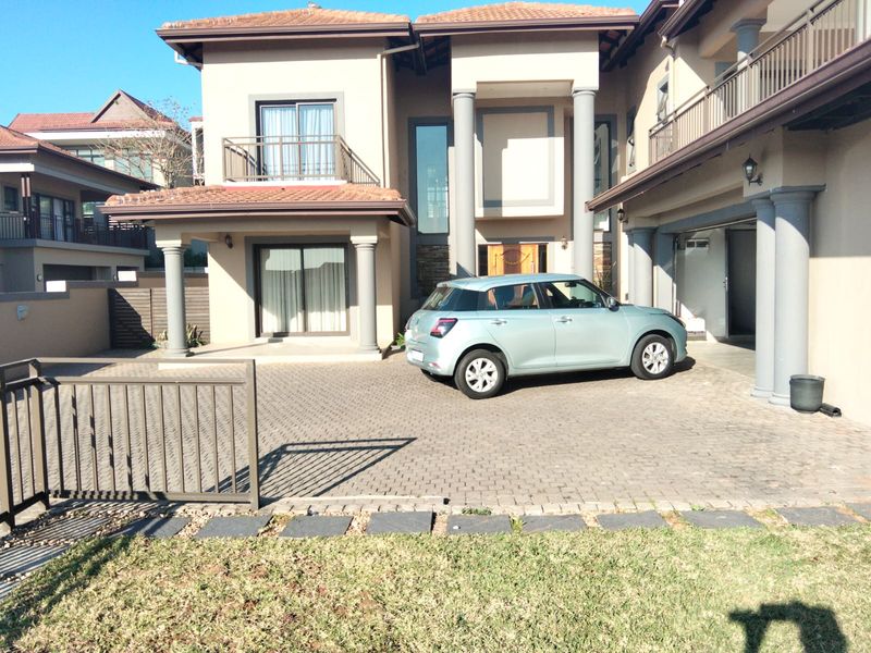 Front elevation of a multi-story residential property featuring a paved driveway, balcony, and integrated garage.