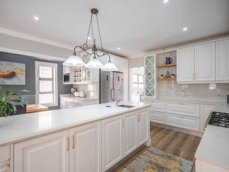 Modern, well-appointed kitchen featuring a central island with stone countertops, ample white cabinetry, gas cooktop, and high-quality finishes throughout.