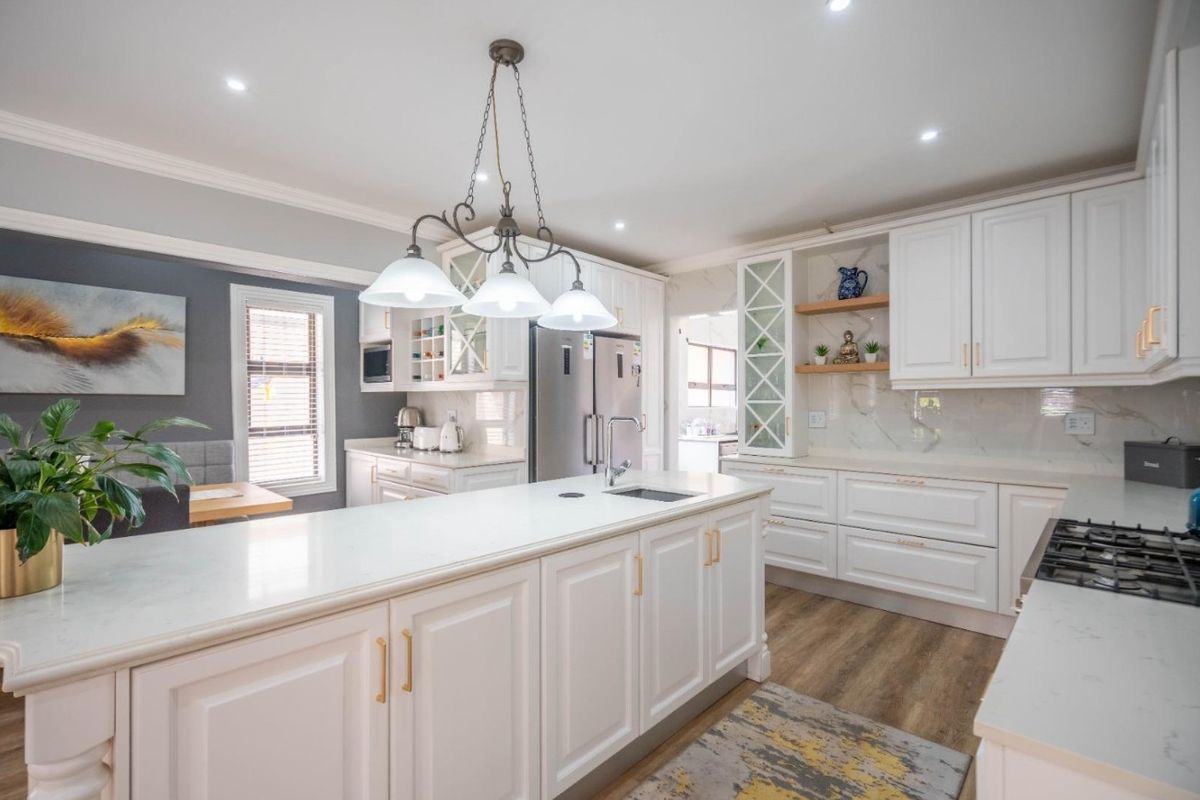 Modern, well-appointed kitchen featuring a central island with stone countertops, ample white cabinetry, gas cooktop, and high-quality finishes throughout.