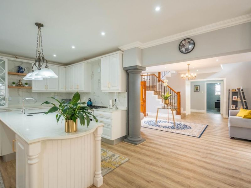 Spacious open-plan kitchen featuring a central island, stone countertops, and shaker-style cabinetry, seamlessly flowing into the entrance hall with a feature staircase.