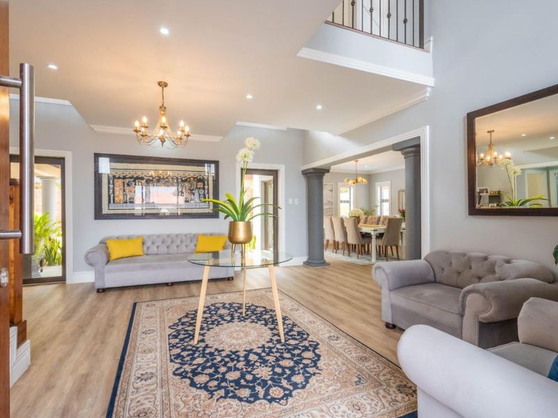 Spacious and elegant entrance hall featuring high ceilings, recessed lighting, decorative columns, and seamless flow into the adjacent dining area.