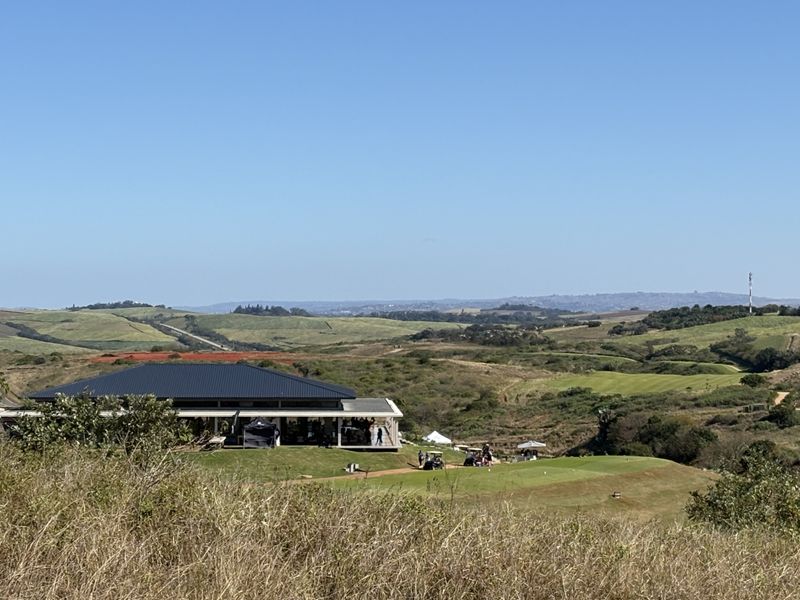 A scenic elevated view overlooking a golf course and clubhouse set within a rolling landscape.