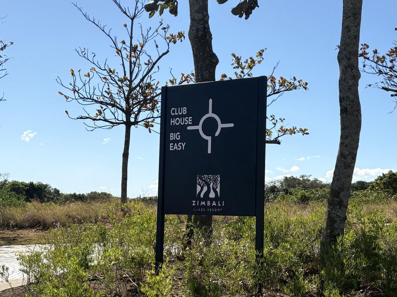 A clear directional sign for the Zimbali Lakes Resort clubhouse and Big Easy facility, set within a landscaped garden area.