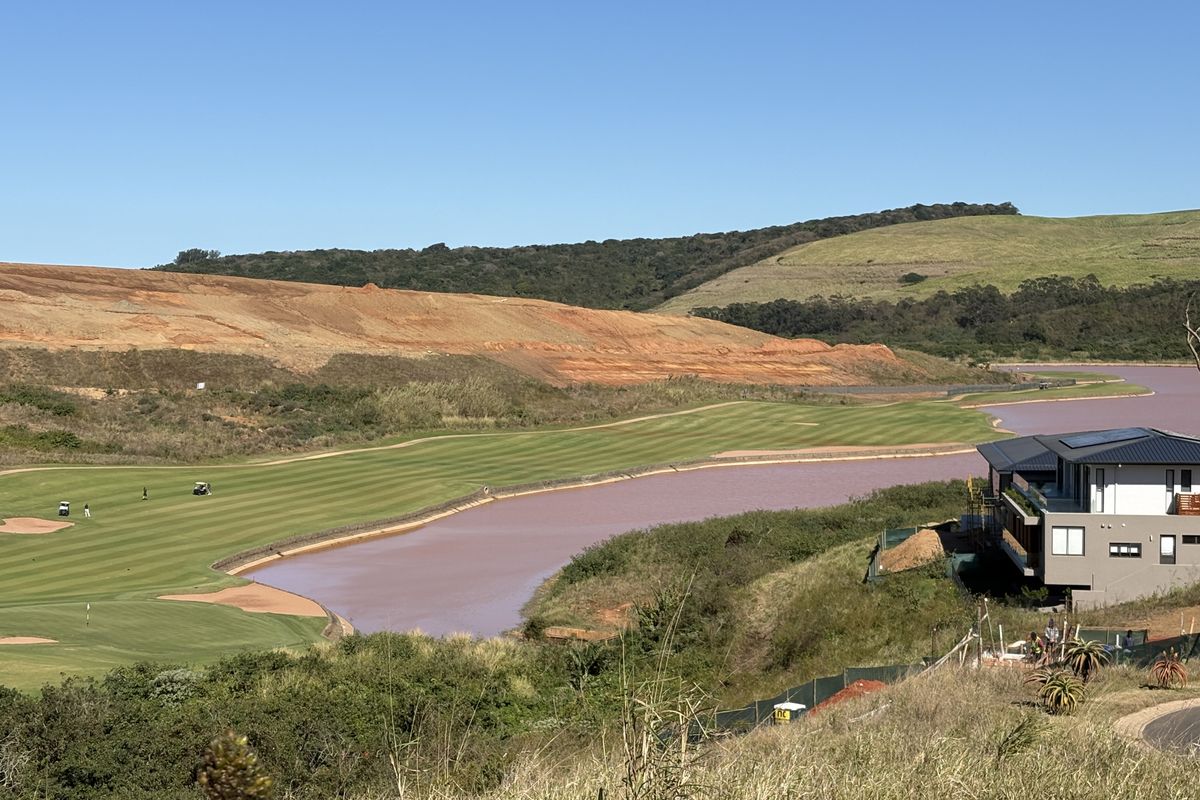 Scenic elevated view overlooking a golf course, water feature, and surrounding natural landscape.