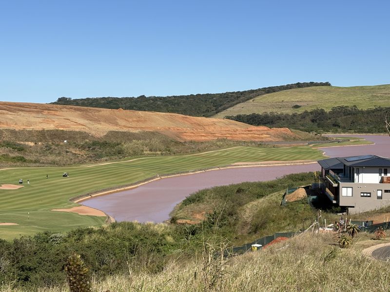 Scenic elevated view overlooking a golf course, water feature, and surrounding natural landscape.