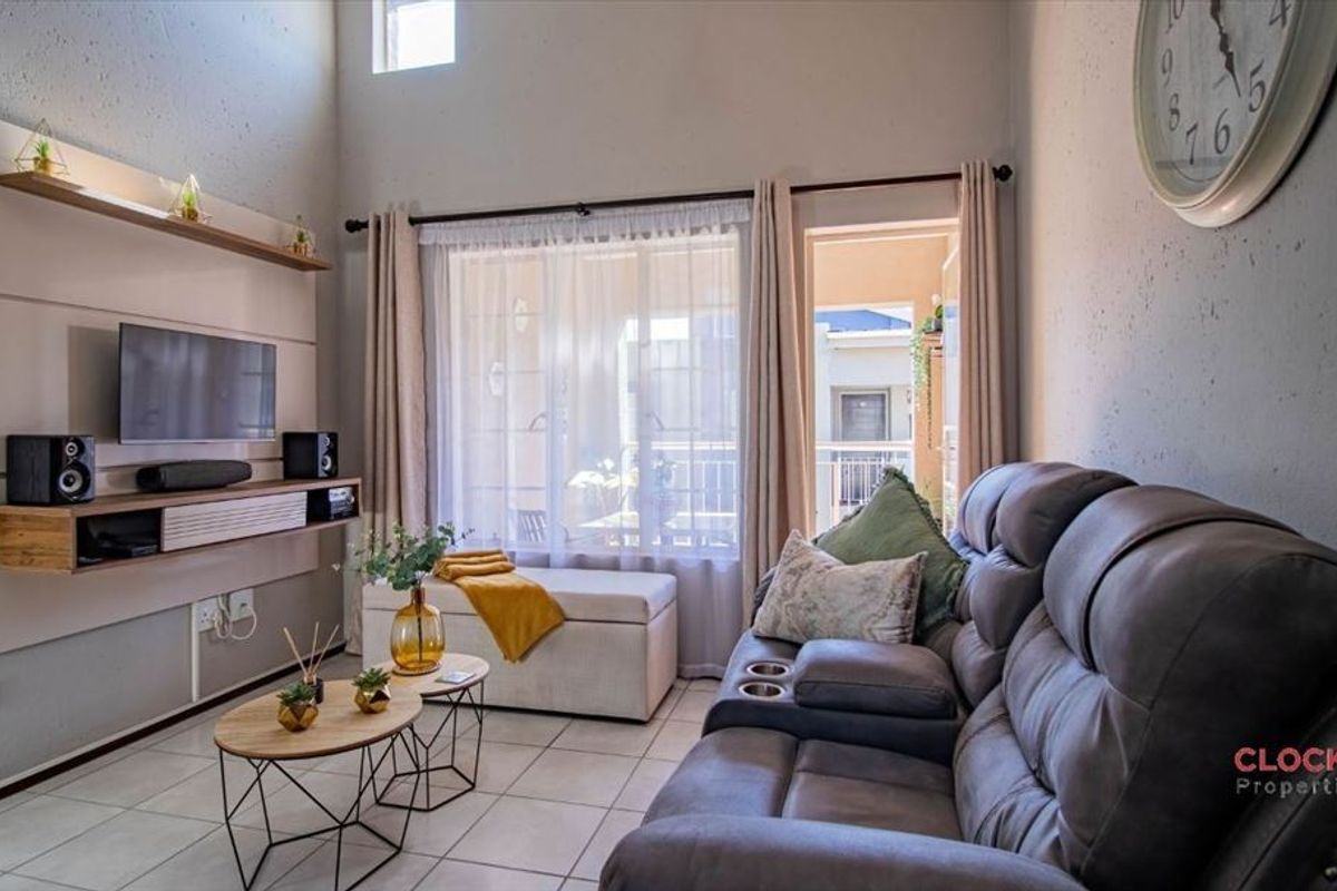 A bright living room featuring high ceilings, tiled flooring, and a built-in media console, with direct access to an outdoor balcony.