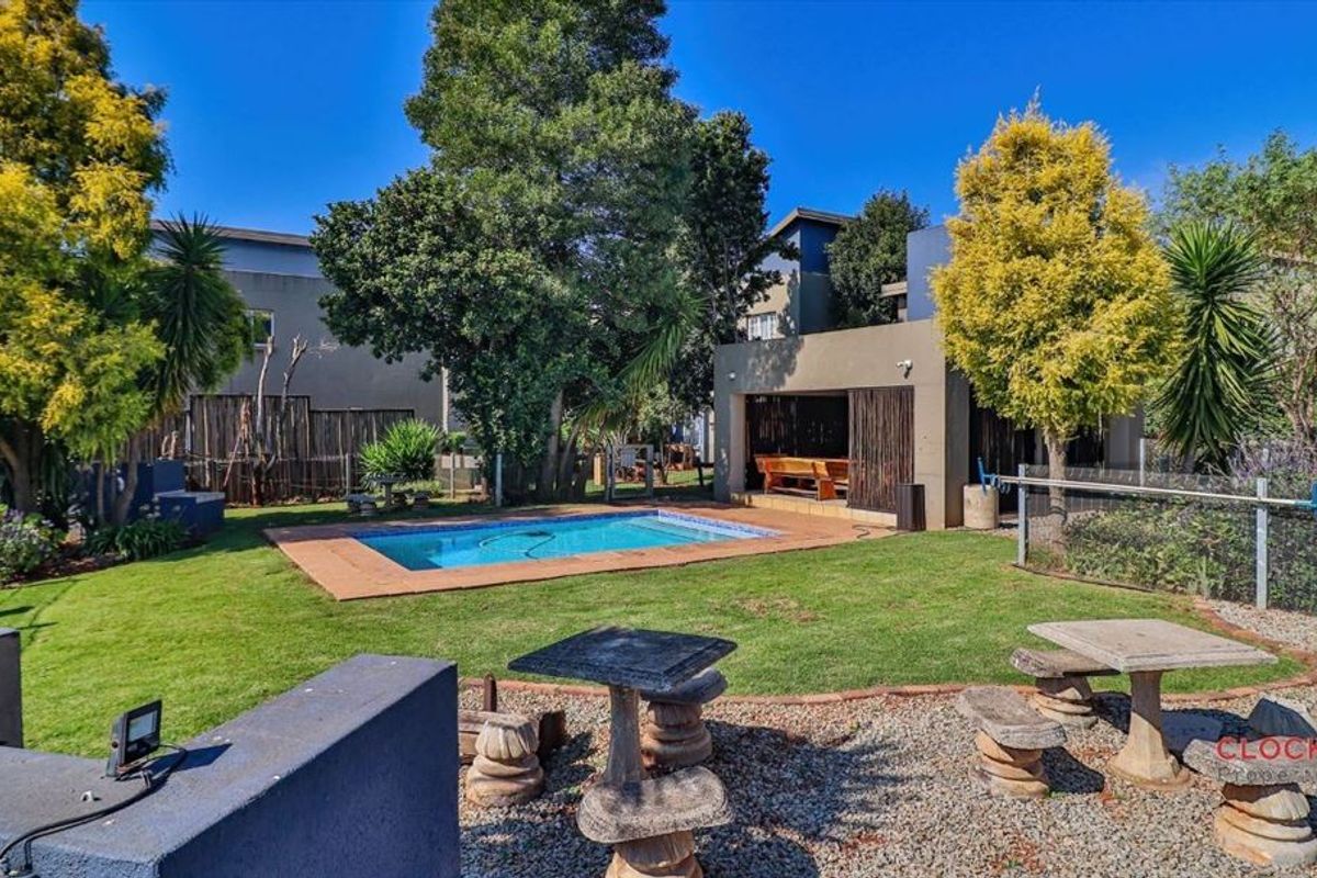 A private rear garden featuring a swimming pool, a covered patio area, and established landscaping within a fenced yard.