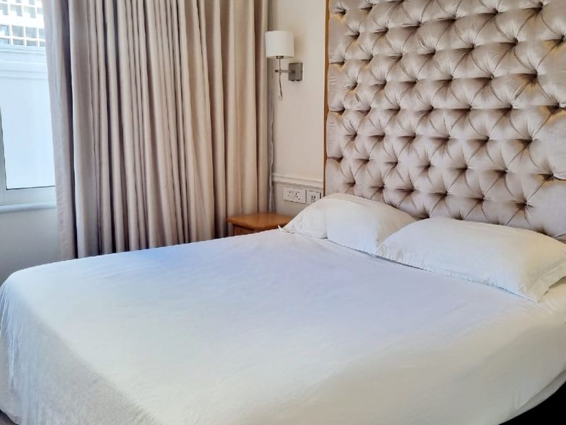 A well-maintained bedroom featuring crown molding, laminate flooring, and wall-mounted lighting, creating a comfortable and polished living space.