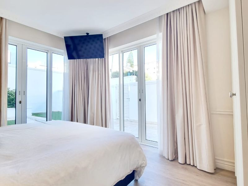 Bright bedroom featuring light laminate flooring, recessed downlights, and double glass doors providing direct access to the outdoor area.
