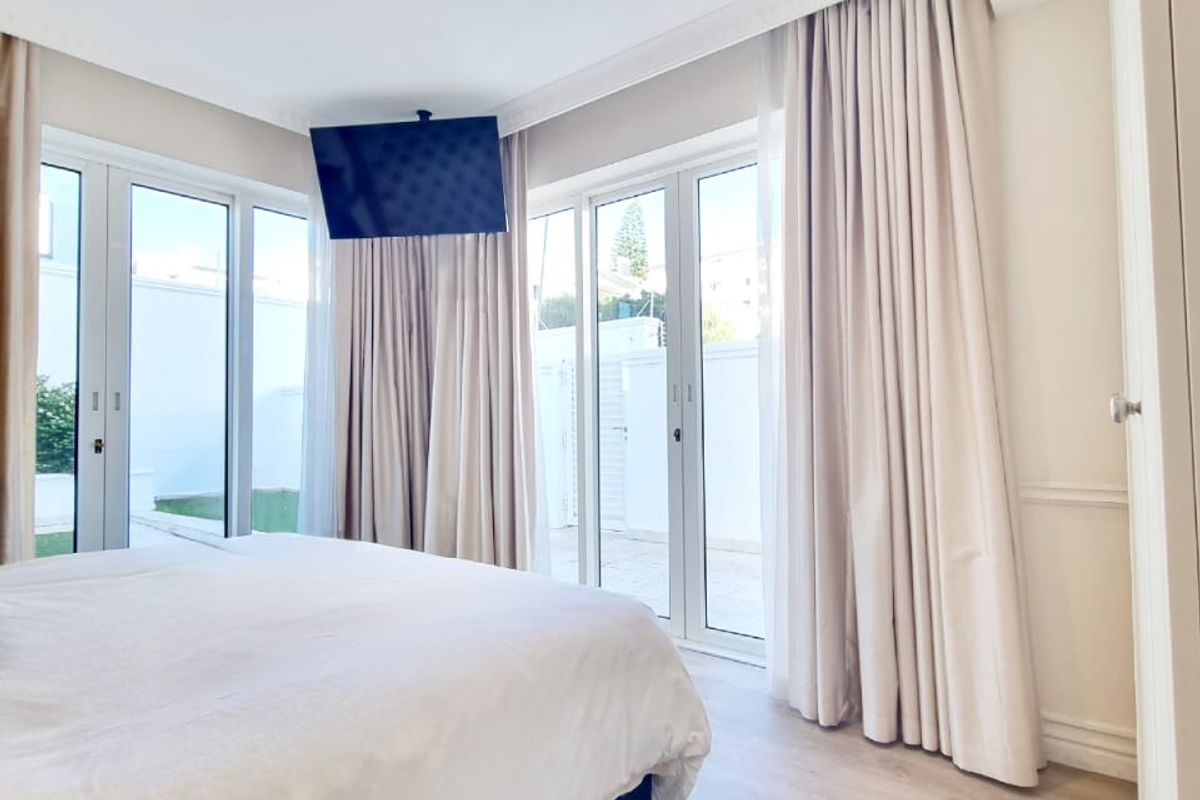 Bright bedroom featuring light laminate flooring, recessed downlights, and double glass doors providing direct access to the outdoor area.