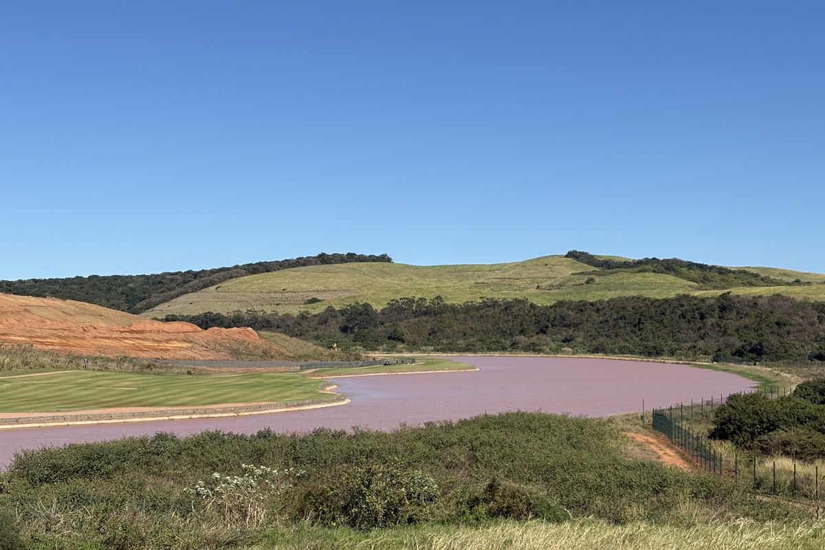 A scenic view of a lake, rolling green hills, and a golf course landscape.