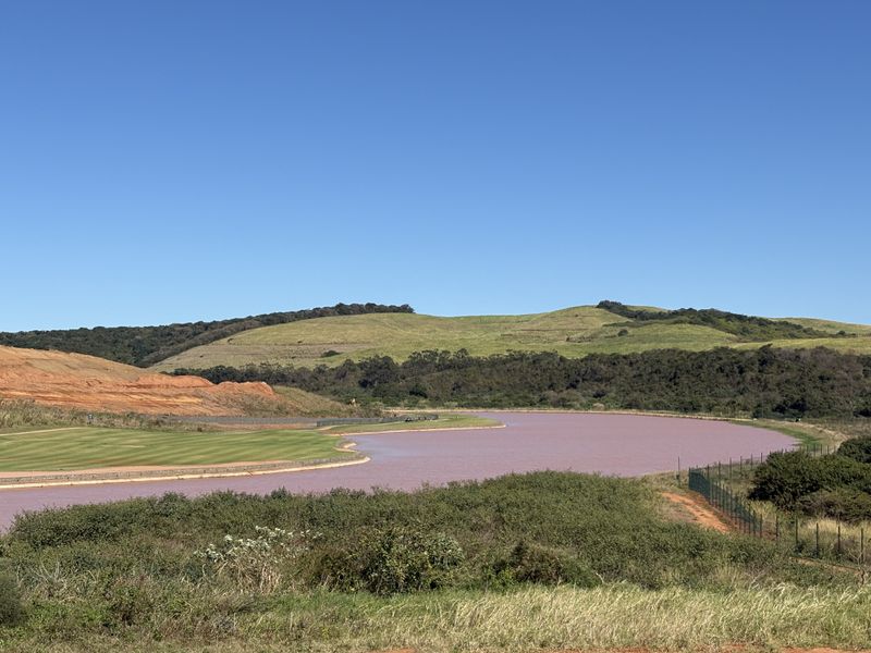 A scenic view of a lake, rolling green hills, and a golf course landscape.