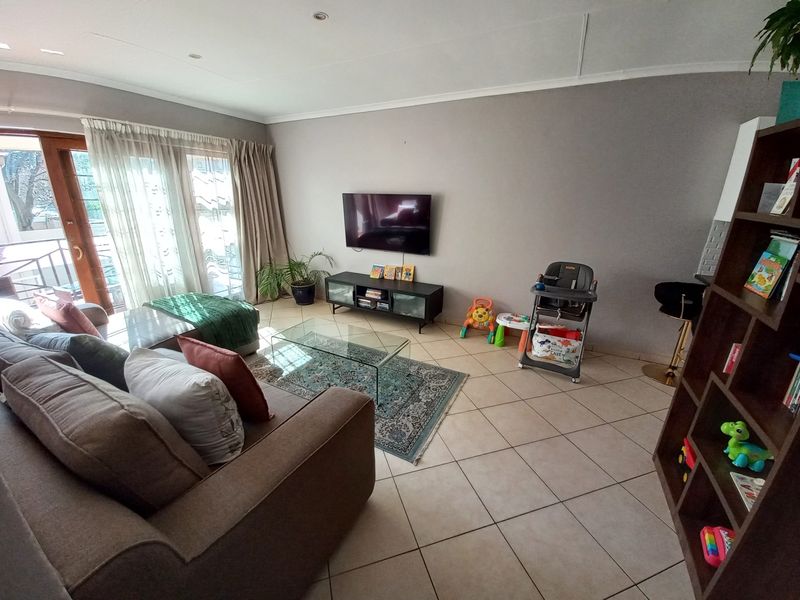 A spacious living room featuring neutral tiled flooring, recessed lighting, and a large sliding glass door providing access to the outdoor area.