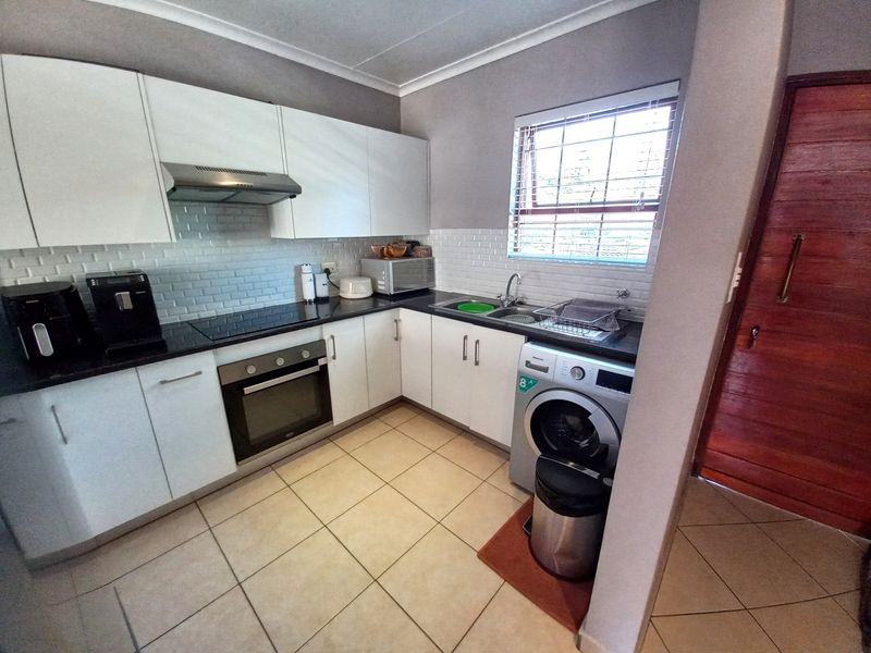 A well-maintained kitchen featuring white cabinetry, black granite countertops, subway tile backsplash, and integrated appliances, including a built-in oven and hob.