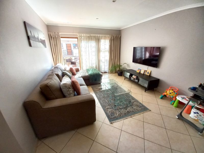 A comfortable living room featuring tiled flooring, recessed lighting, and a sliding glass door providing access to an outdoor balcony area.